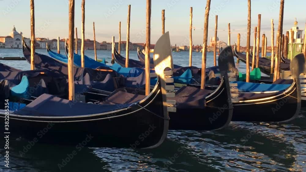 Parked Venice gondolas rocking on water at sunrise Parked Venice gondolas rocking on water at sunrise