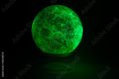 glowing green spheres fluorite on a black background looks like a planet or moon
