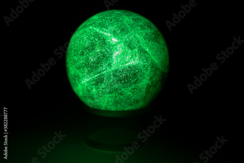 glowing green spheres fluorite on a black background looks like a planet or moon © Chris
