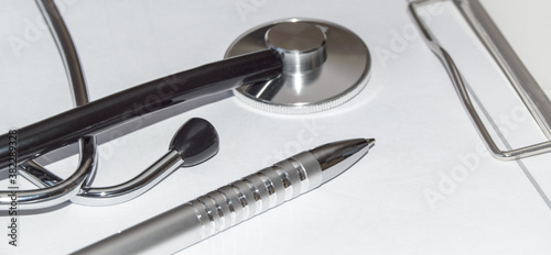 Close-up of a doctor's desktop with a medical stethoscope and pen on a white background, medicine concept