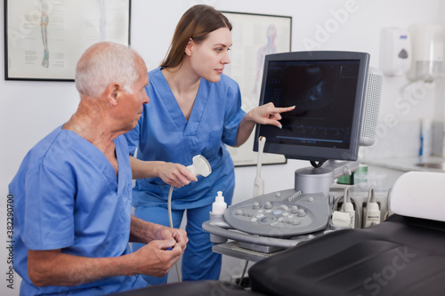 Skilled and experience sonographer showing and explaining a new equipment to assistant photo