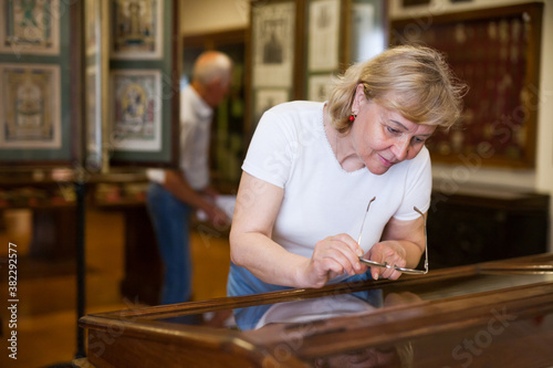 Senior woman looking at exhibit on exposition of historical museum