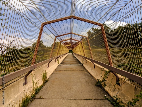 perspective view of a pedestrian overpass being overgrown with weeds