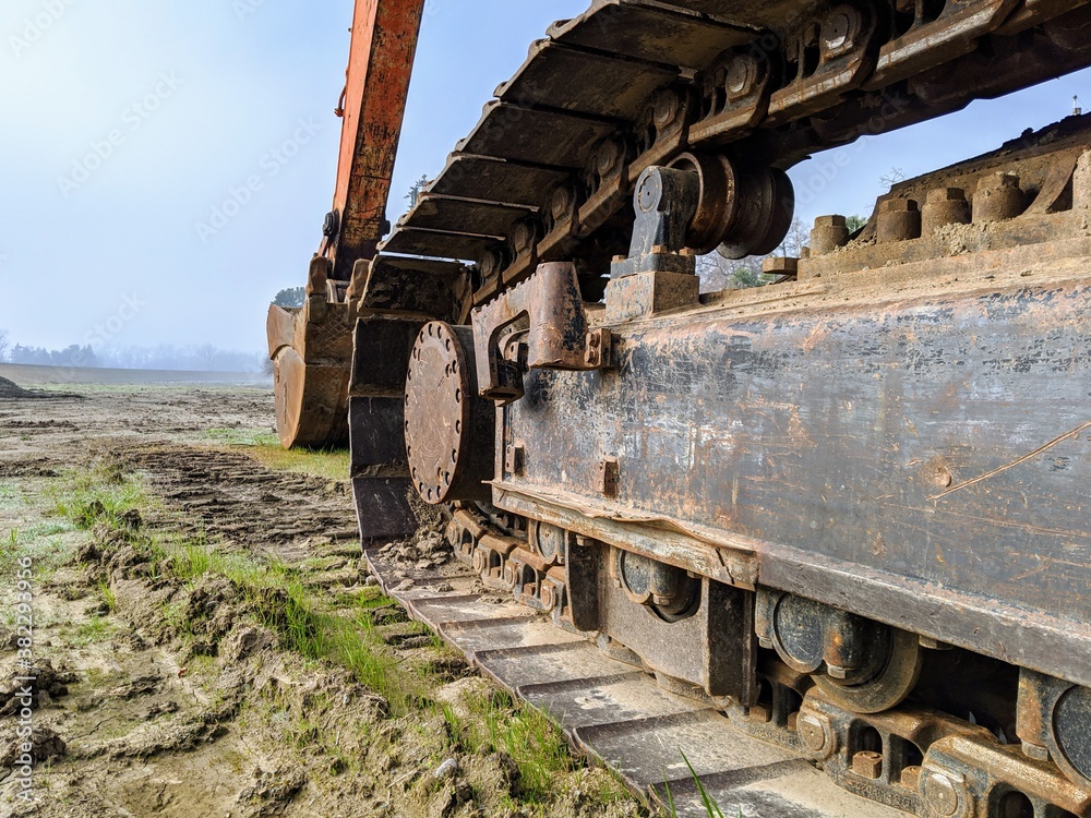 Tracks on an excavator sitting in a muddy field 