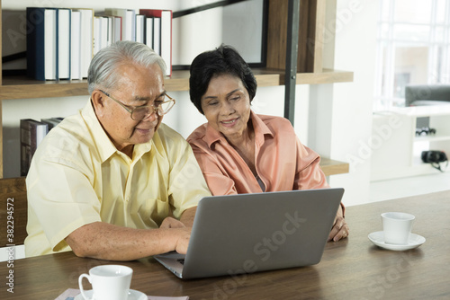 Senior Asian elderly couple in home casual outfit with happy smiling emotion sitting in living room using laptop together