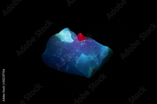 Natural red spinel crystal, mounted on white marble; from Mogok region in Myanmar. Photographed under long-wave UV light; the host rock fluoresces blue, the gemstone bright red. 

 photo