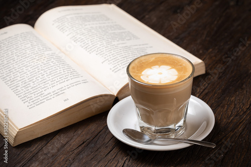 Coffee cup, cappuccino, hot latte, cafe au lait or coffee with milk in a glass cup, open book on the dark wood table. Almond milk, cashew milk, vegan, vegetarian, healthy food, breakfast drink