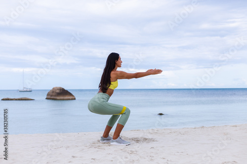 Photos Caucasian attractive slim fit woman wearing pretty sport wear with yellow rubber elastic bands in her hands at beach