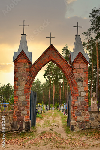 Photo of a red brick Catholic cemetery. The picture was taken at sunset in the fall. photo