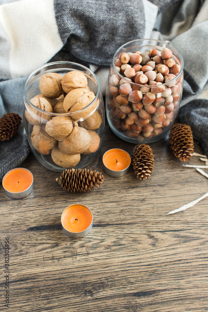 Autumn composition of nuts, cones and candles on a wooden background.
