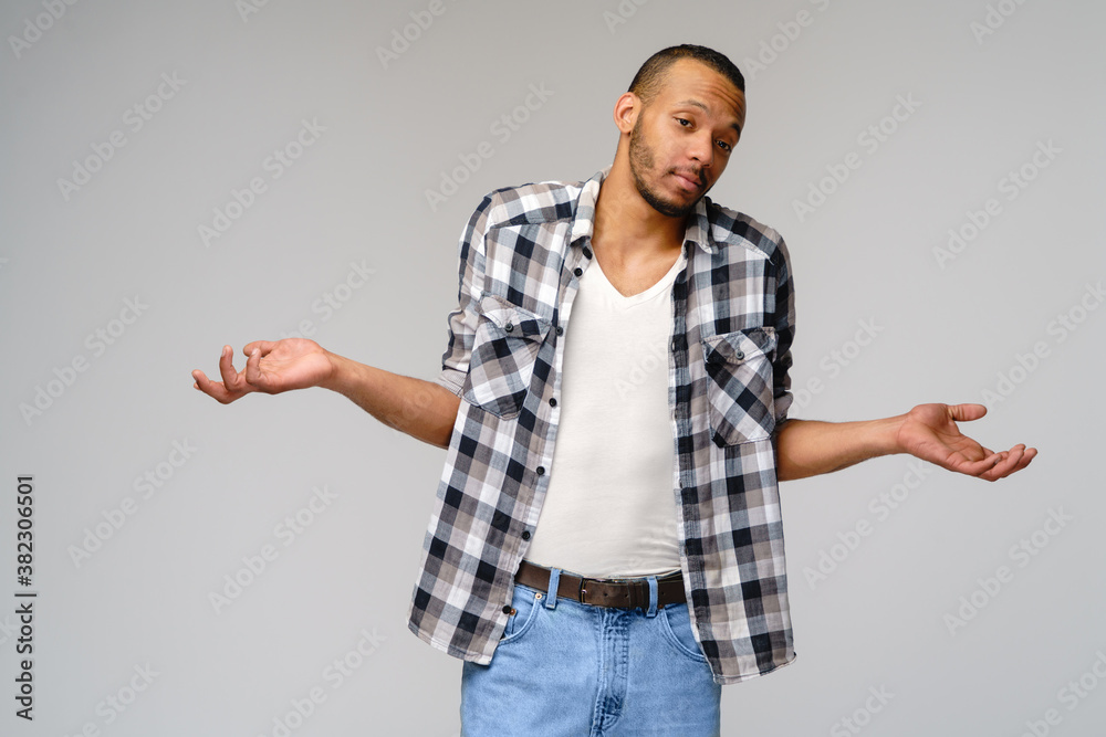 I don't know gesture - Young afrcian american man over grey background being at a loss, showing helpless gesture with arm and hands, as if he does not know what to do I don't know gesture - Young afrcian american man over grey background being at a loss, showing helpless gesture with arm and hands, as if he does not know what to do
