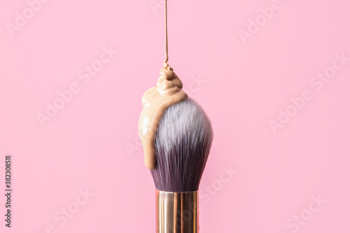 Brush with foundation for makeup on color background photo