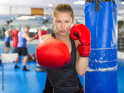 Portrait of happy woman boxer who is training in gym. © JackF