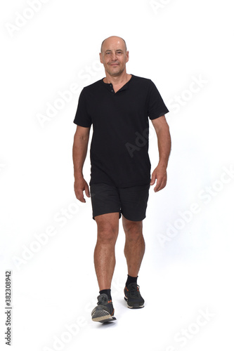 front view of a man wearing with sportswear t-shirt and shorts walking on white background,
