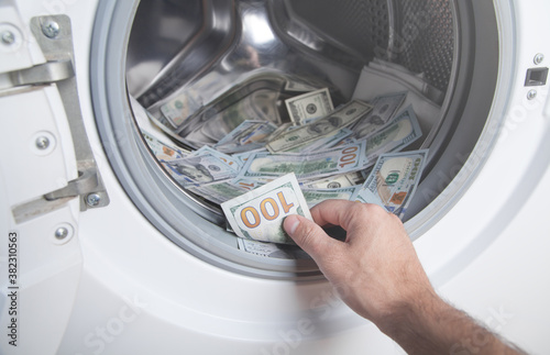 Male hand holding dollar in washing machine. Money laundering © andranik123
