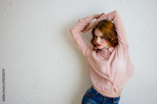 Young woman grimacing on camera at white studio background. Portrait of beautiful girl with ginger lonh hair photo