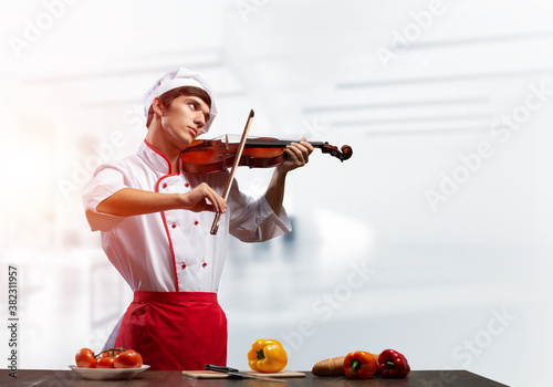 Young male chef with violin standing photo