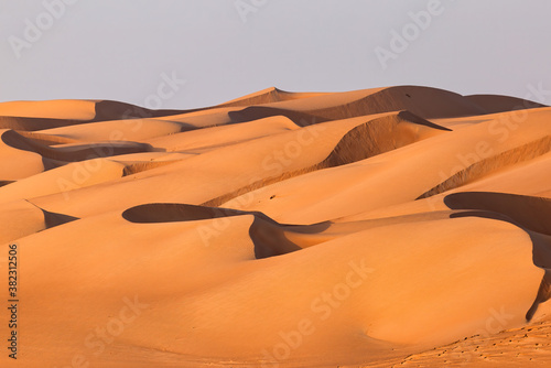 A desert landscape with sand dunes at sunrise in an Arabian desert.