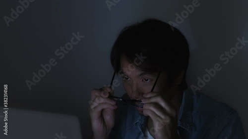 Asian Casual Businessman or Freelance in Jeans Shirt Hold Glasses Typing Laptop and Working Late at Office