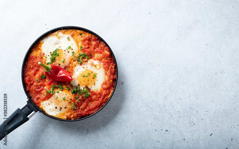 Shakshuka, fried eggs with vegetables in a frying pan, traditional israeli cuisine, top view, place for text