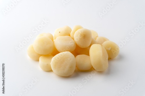 A pile of cooked and peeled water chestnuts on a white background.