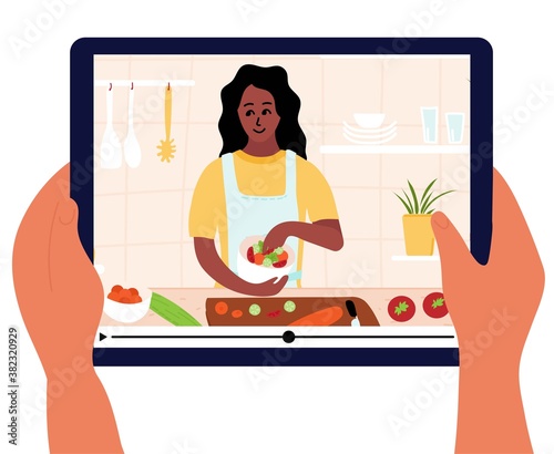 Food blogger is on laptop display. Culinary video broadcast or channel  with cooking online class. Young woman preparing salad in kitchen. Hand holding digital tablet. Healthy food at home. 
