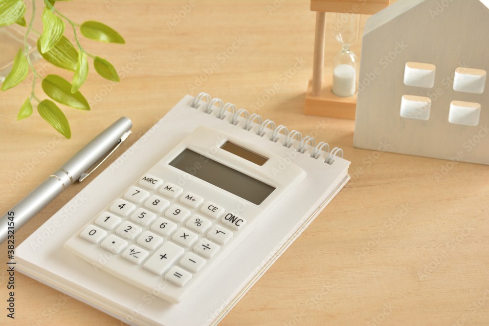 Calculator and house on a wooden table Calculator and house on a wooden table