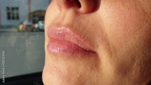 Close up view of beautiful woman lips with purple glossy lipstick. Open mouth with white teeth. Cosmetology, drugstore or fashion makeup concept. Passionate kiss