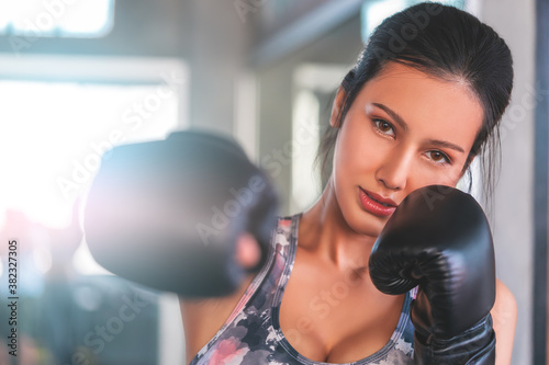 Asian woman is throwing Boxing punch into the camera in an indoor gym working out for fitness and healthy lifestle. photo