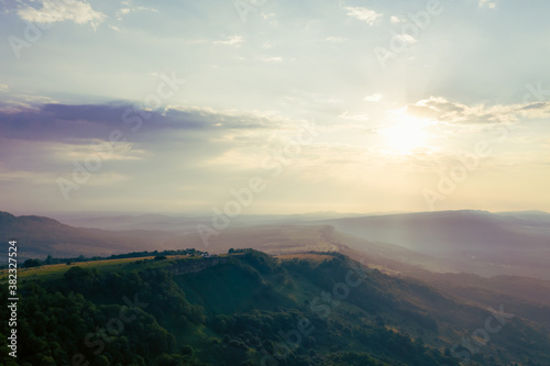 Early morning in the mountains. Morning sun and haze in the valley against the background of mountains. Mountain summer landscape
