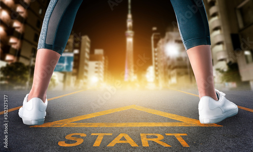 Fotografie Woman runner legs is standing on a start sign ready to run to goal and freedom on Tokyo night city skyline for motivation begining concept