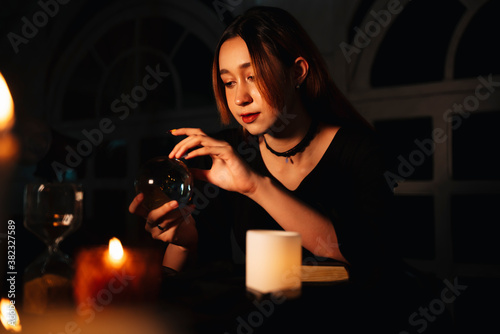 Beautiful long hair woman fortune teller with crystal ball in dark room.