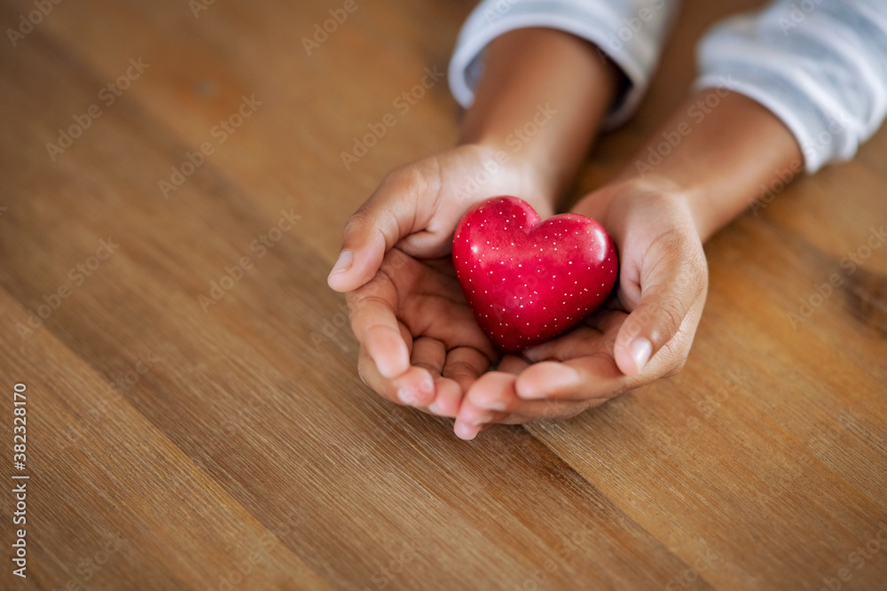 Little child holding red heart in her hands