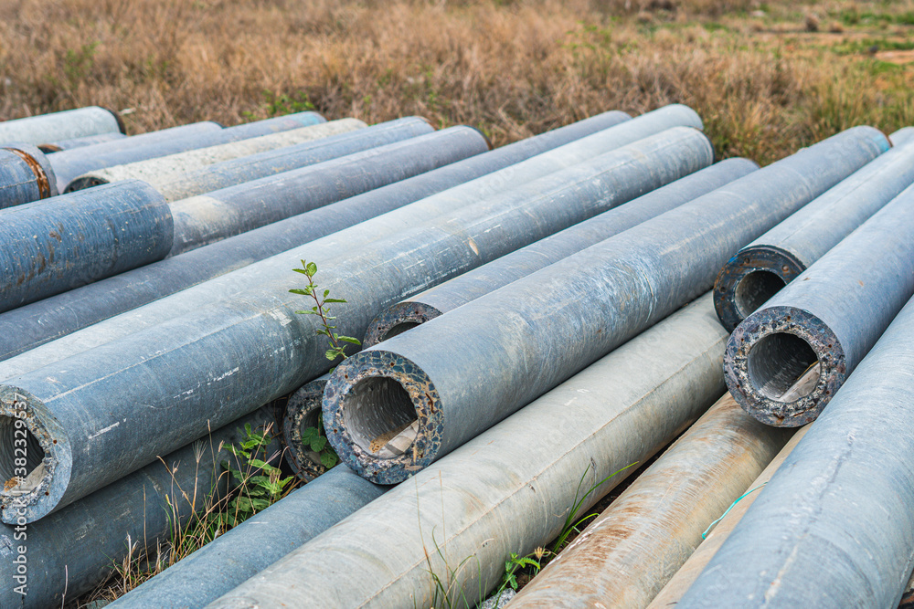Stack of concrete pipes at a construction site outdoors warehouse. Civil infrastructure, industry manufacturing of cement products Stack of concrete pipes at a construction site outdoors warehouse. Civil infrastructure, industry manufacturing of cement products