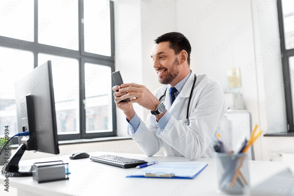 healthcare, medicine and people concept - smiling male doctor with smartphone at hospital healthcare, medicine and people concept - smiling male doctor with smartphone at hospital