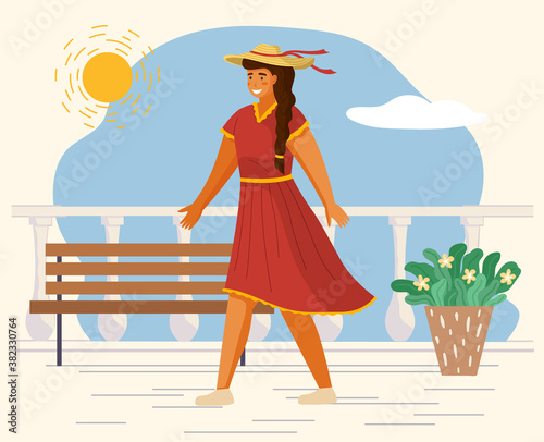 Beautiful girl in a straw hat in summer day outdoor. Young cheerful woman walking on the white seafront. Smiling female character wearing red light dress. Elegant pretty girl on a terrace with bench