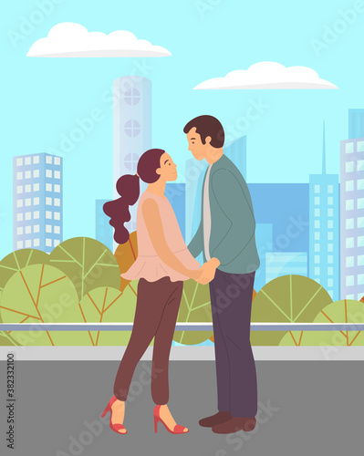 Couple walking in a city park. Young guy and girl holding hands, looking into each other s eyes, romantic walk. Lovers man and woman met on a date outdoor. Romantic promenade in the open air