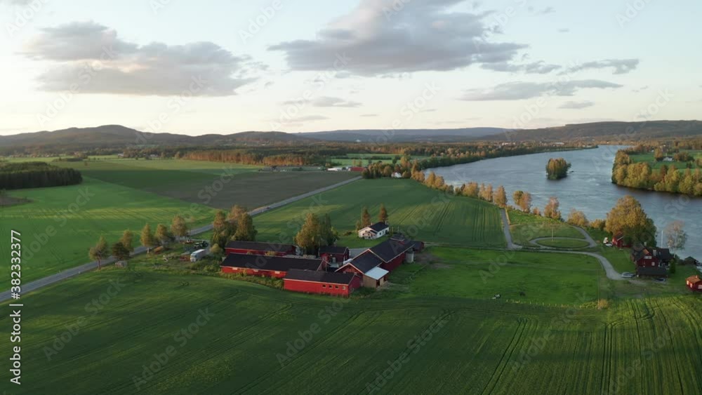 Swedish summer nature landscape aerial drone video. Beautiful traditional red house by a natural blue river and forest. Typical Sweden view on sunny afternoon or sunset evening