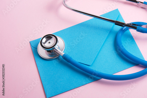 stethoscope and blue envelope on pink background doctor s day  health care day concept
