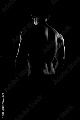 Rear view of young muscular man in black and white. Nude silhouette of Back.