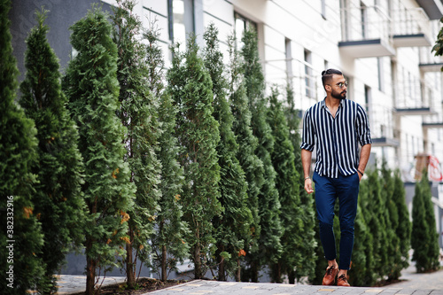 Successful arab man wear in striped shirt and sunglasses pose outdoor.