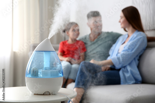 Modern air humidifier and blurred family on background