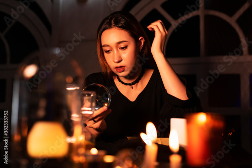 Beautiful young woman fortune teller looking at crystal ball to predict the future.