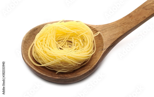 Raw egg pasta noodles in wooden spoon, isolated on white background