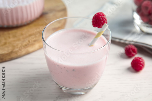Tasty fresh milk shake with raspberry on white table, closeup