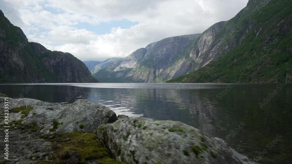 Gimbal walking shot of Norwegian lake in natural fjord mountain landscape. Summer in Norway. Low angle view Gimbal walking shot of Norwegian lake in natural fjord mountain landscape. Summer in Norway. Low angle view