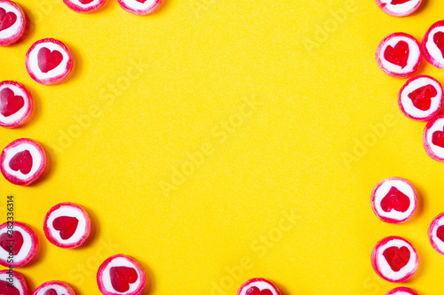 Candy hearts on bright yellow background with copy space in the middle