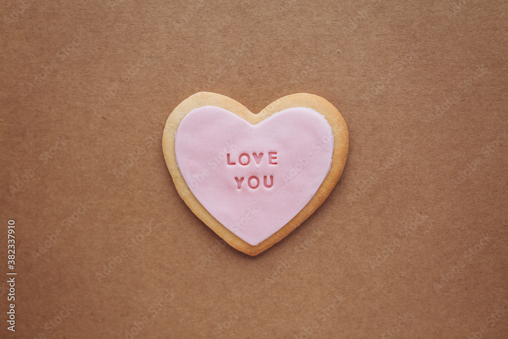 Heart shaped cookies with pink glaze and the inscription: «love you» located on a craft paper background with space for your text..Valentine's Day gifts Heart shaped cookies with pink glaze and the inscription: «love you» located on a craft paper background with space for your text..Valentine's Day gifts