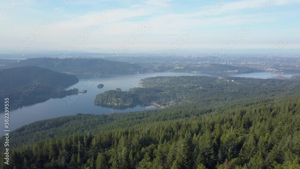 Vancouver Indian Arm and Deep Cove from high above over forest. Drone Aerial shot of green pine trees, blue water, buildings, skyline in the distance. Summer morning light in British Columbia Canada Vancouver Indian Arm and Deep Cove from high above over forest. Drone Aerial shot of green pine trees, blue water, buildings, skyline in the distance. Summer morning light in British Columbia Canada