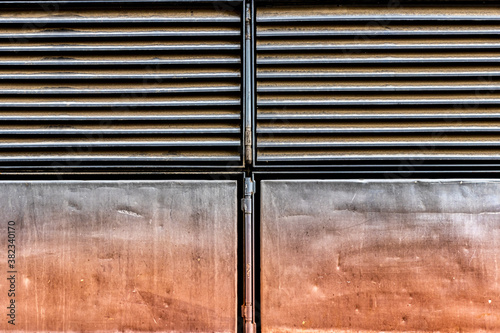 Close up macro shot of an industrial doorway leading into a factory. Details of aged steel sheets, ventilation blades, and grungy textures. Symmetric geometry, prefab elements, natural light